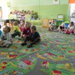 Dzieci siedzą po turecku na dywanie