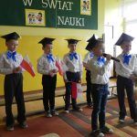 chłopiec przemawia na tle dzieci z polskimi flagami